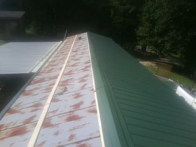 Old rusted panels beside newly installed green metal roofing — Wind Damage Roof Repair by Roofing Brothers in Northridge