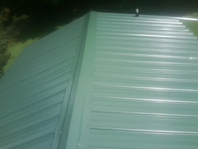 New green metal panels meeting at the ridge of a roof — Flat Roof Repair work by our crew in Northridge