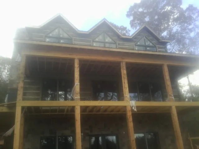 Dormers and porch framing on a large log home under construction — Roof Coating work by our crew in Northridge