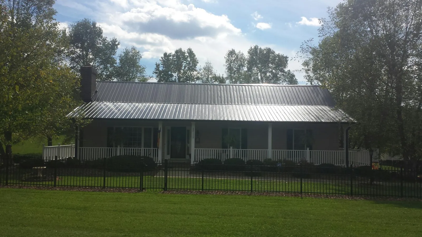 Gray metal roof on a brick ranch with a full width front porch — Gutter Guard Installation work by our crew in Northridge