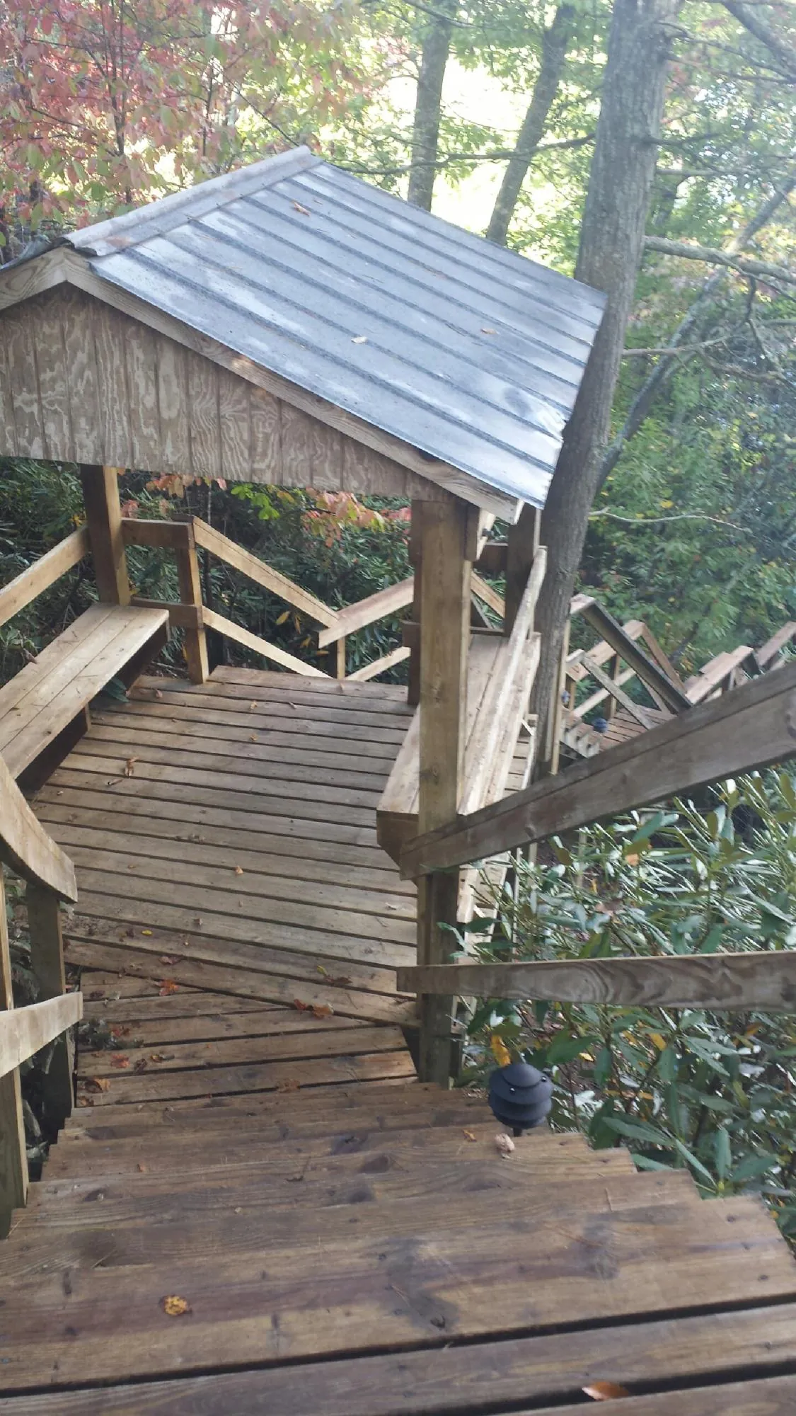 Metal roofed shelter over wooden steps on a wooded walkway — Skylight Repair & Installation work by our crew in Northridge