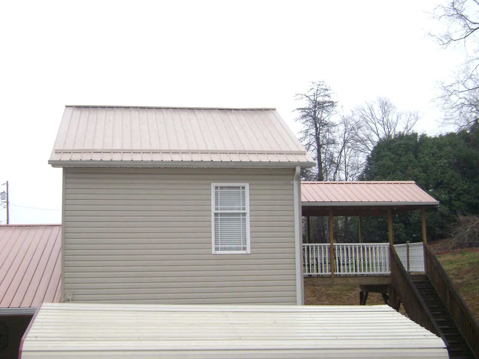Tan metal roofs on a two story addition and attached porch, from a Roof Replacement job in Northridge