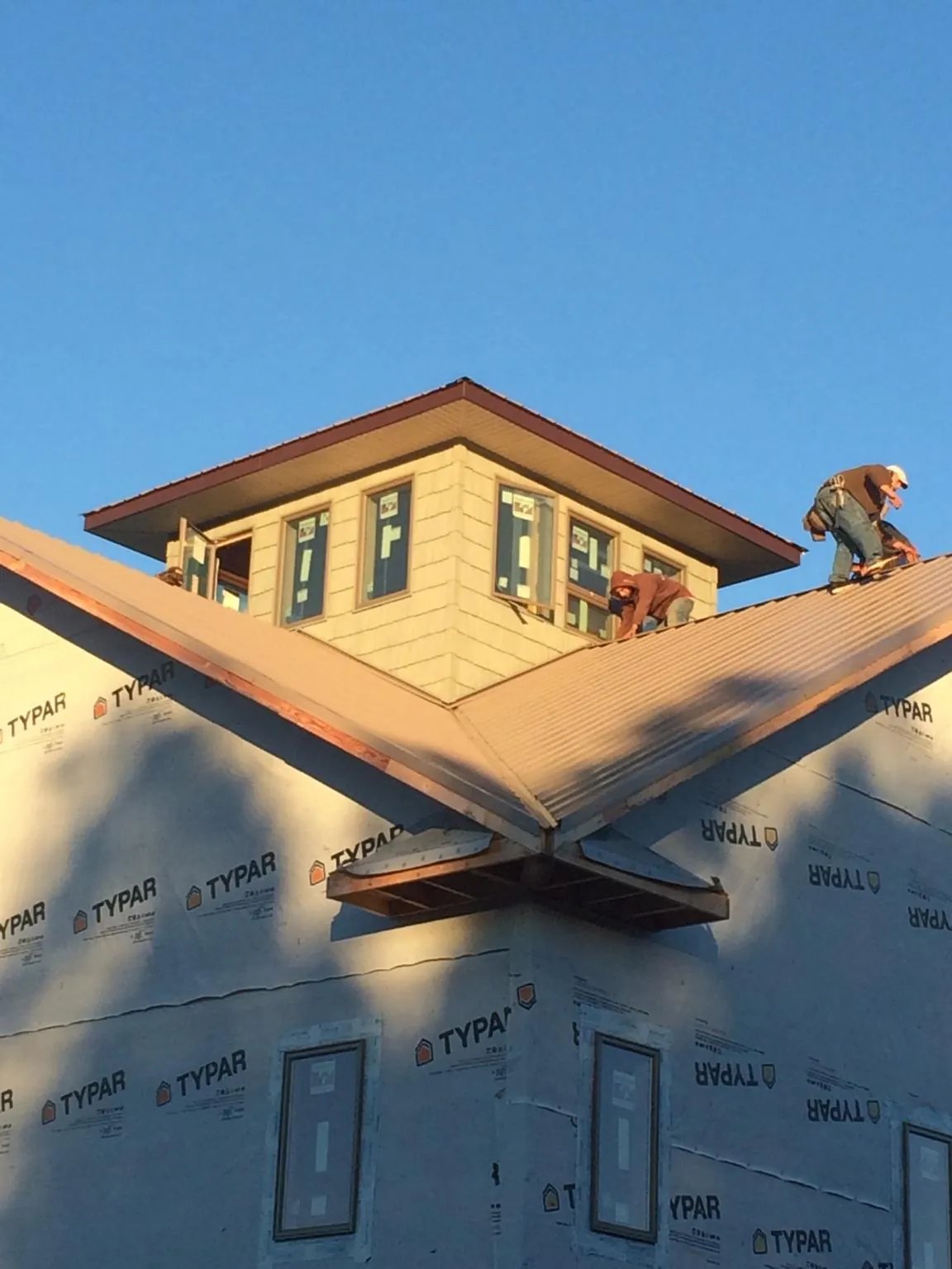 Roofers working around a rooftop cupola on a new metal roof at sunset — Roof Waterproofing in Northridge by Roofing Brothers